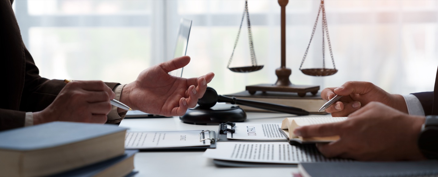 Attorneys and a medical expert reviewing case documents beside the scales of justice