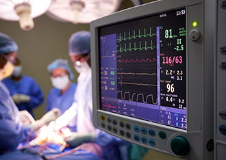 Surgical team operating beside a patient vitals monitor